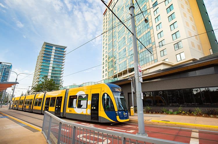 A Yellow Train Traveling Down Train Tracks Near A Building