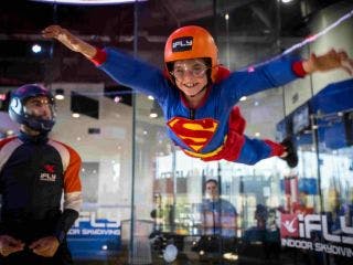 Boy worn like a superman playing in a skydiving simulator