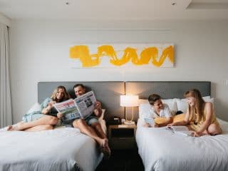 two couples in a bedroom, talking and laughing with each other